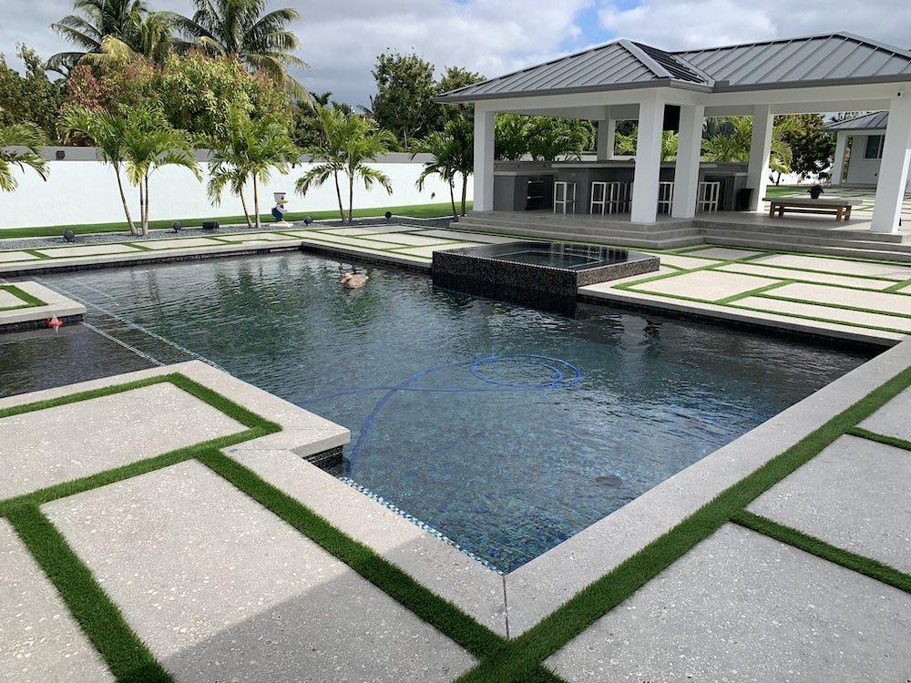 Geometric rectangular pool with a raised tiled spa and tropical landscaping in a Miami backyard