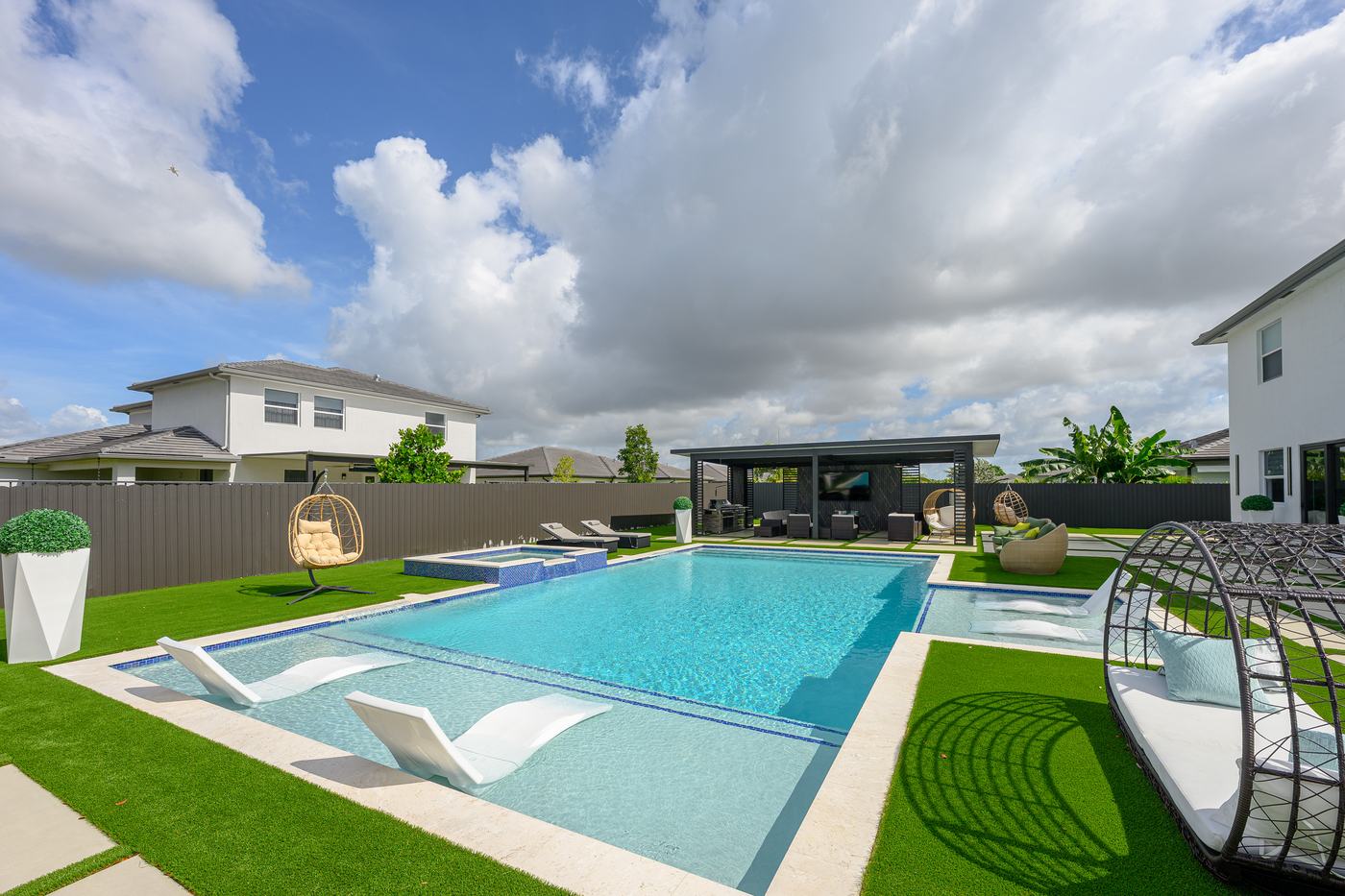 Modern poolside pergola in a fully landscaped backyard built by Dream Pools FL in Miami-Dade County