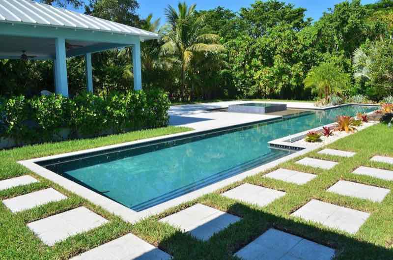 Rectangular pool with raised spa and covered cabana, stepping-stone pavers across turf