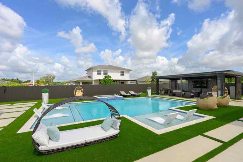 Pool with white in-pool loungers, a covered cabana, and outdoor sectional seating