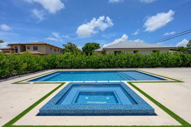 Rectangular pool with matching raised square spas at each end, bordered by turf