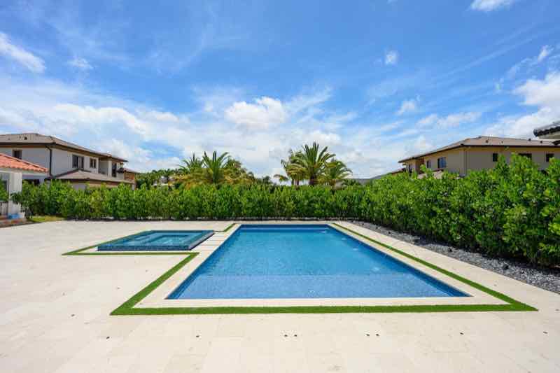Rectangular pool with a small raised spa on a turf-and-travertine deck