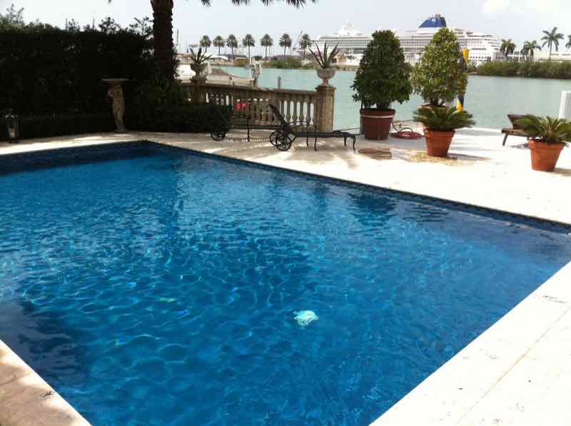 Rectangular pool with a waterfront marina view in the background