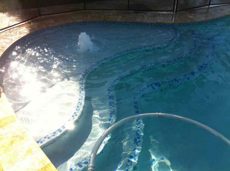 Close-up of pool steps and tile finish with sunlight reflecting on the water