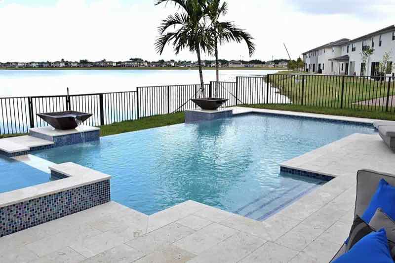 Waterfront pool with raised mosaic-tile spa and lounge seating overlooking a canal