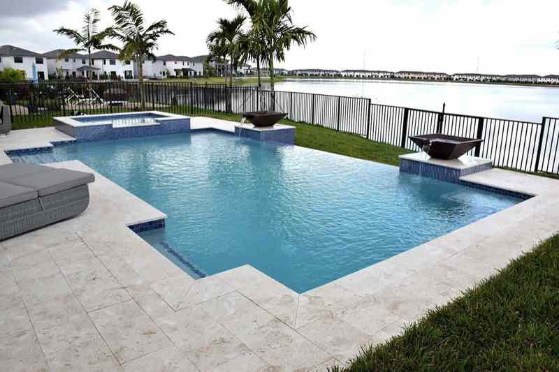 Waterfront freeform pool with travertine deck and canal view in the background