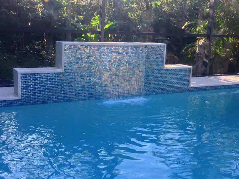 Pool with a mosaic-tile raised wall and sheer-descent waterfall feature