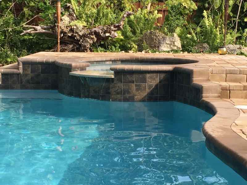 Freeform pool with a raised stacked-stone spa and waterfall feature