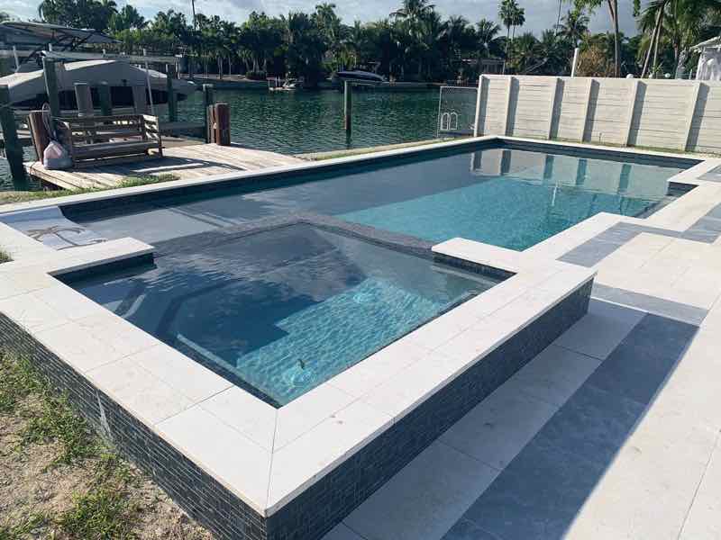 Rectangular pool with matching raised spa overlooking a canal at sunset