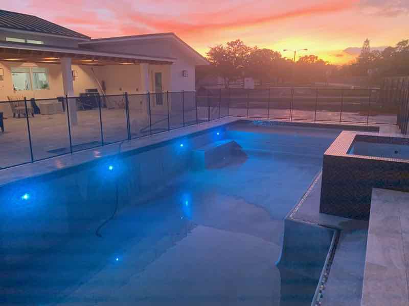 Rectangular pool with underwater LED lighting glowing blue at dusk