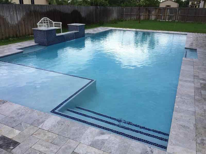 Rectangular pool with tanning ledge and matching raised stone fountain accent