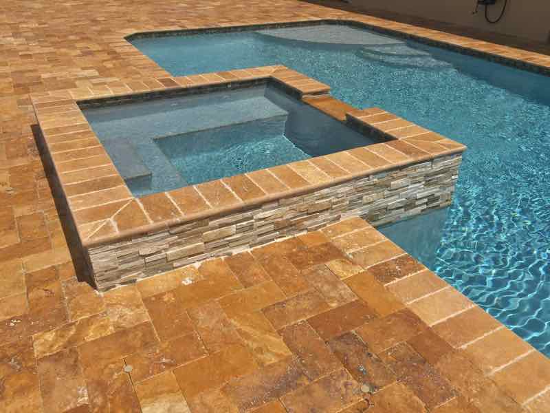 Rectangular pool with raised mosaic-tile spa on a brick-paver deck