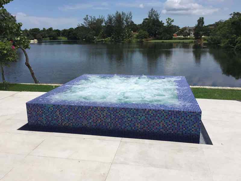 Raised square spa with bubbling jets overlooking a lake