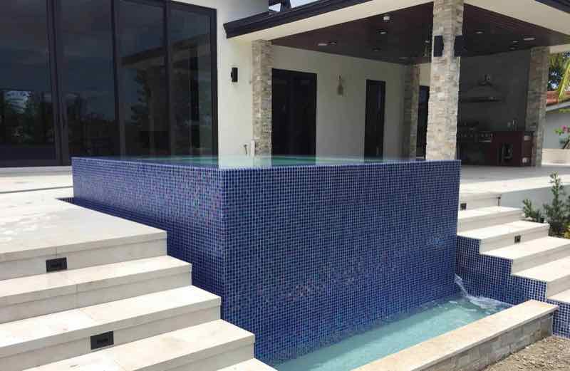 Elevated mosaic-tile spa and waterline built into a staircase-level patio