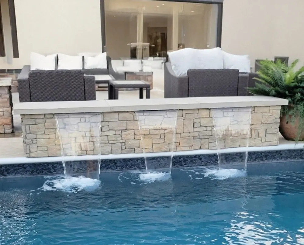 Sheet waterfalls cascading over a stone wall into a custom pool built by Dream Pools FL in Miami-Dade County