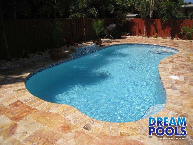 Custom pool with tiled edge, stone patio, and tropical landscaping in Miami-Dade County